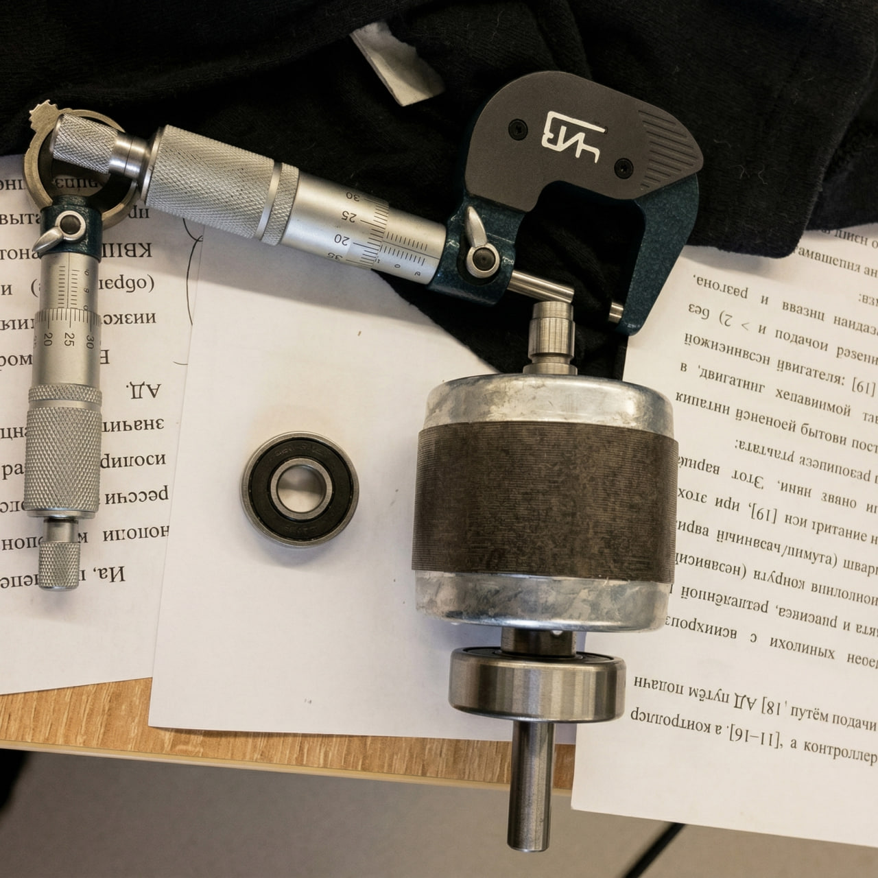 Micrometer on a Slavyanka stator over scientific publication pages — precision measurement workflow