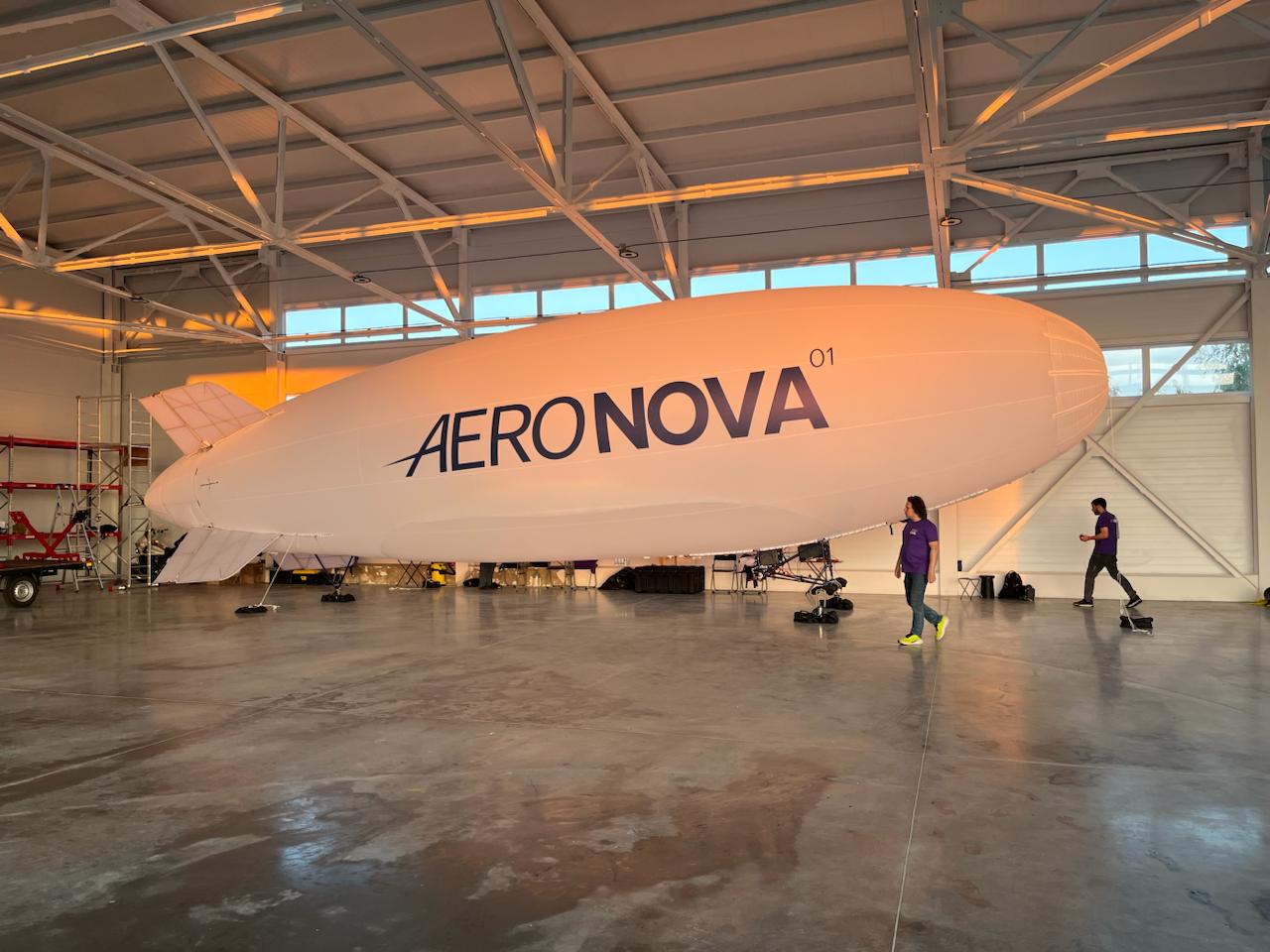 NOVA-01 in the hangar at sunset · scale reference with people